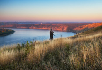 Obraz premium the photographer shoots the canyon of the picturesque river. tourist on the rock. autumn morning 