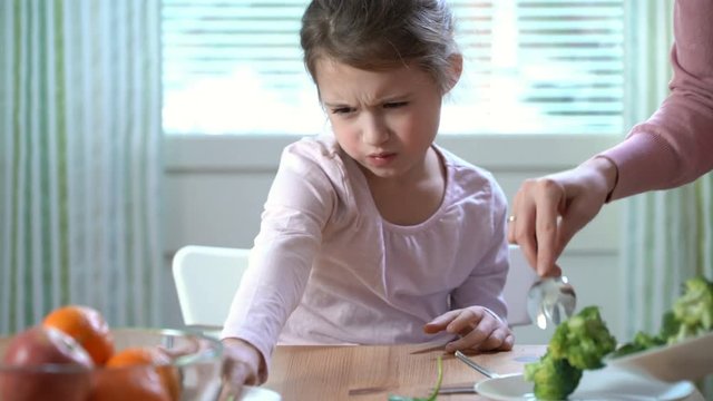Little girl do not want to eat vegetables and dislike taste of broccoli and spinach. The concept of healthy baby food