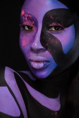 Fashion portrait of beautiful girl with bright pigment, creative art make-up, abstract face art on black background