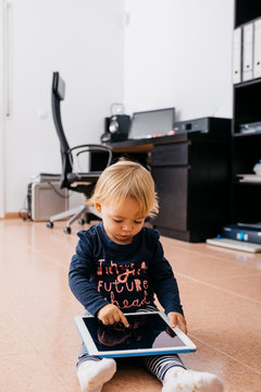 Little girl sitting on the floor at home using tablet