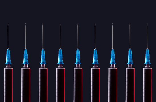Multiple syringes organized in a pattern over dark background