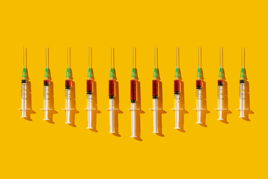 Multiple syringes organized in a pattern over yellow background