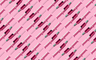 Multiple syringes organized in a pattern over pink background