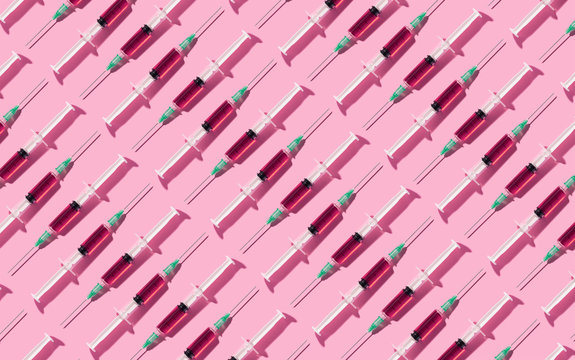 Multiple syringes organized in a pattern over pink background