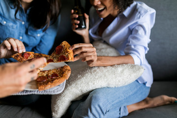 Close-up of cheerful friends drinking beer and eating pizza