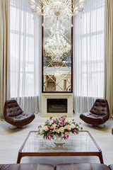 Mirror over fireplace and leather armchairs around.