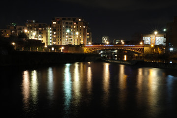 Fototapeta na wymiar the river aire in leeds at night showing buildings on both sides of crown point bridge and the weir