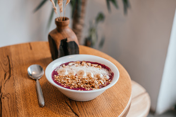 Beautiful blueberry banana smoothie bowl with a spoon on wooden table. Healthy breakfast concept.