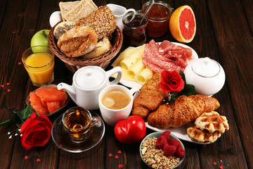 breakfast on table with bread buns, croissants, coffe and juice on valentines day.