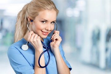 Attractive young female doctor with blurred hospital interior on