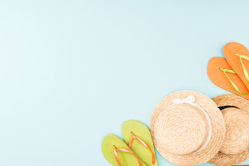 top view of straw hats and flip flops on blue background