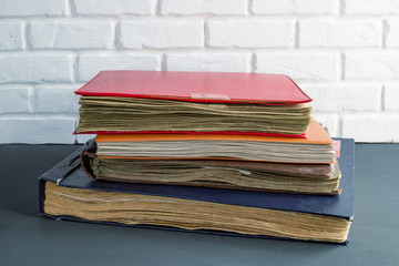 a stack of old photo albums against a brick wall