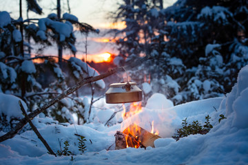 Fireplace and coffee pot in Finland. There is a sunset in the background. There is a lot of snow...