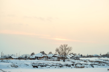 Snowy landscape of lakeside with village at sunrise 