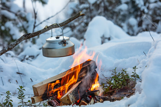 Fireplace and coffee pot in Finland. There is a sunset in the background. There is a lot of snow and frost.