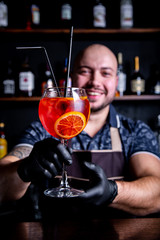 Barman puting to glass of fresh and tasty Aperol syringe cocktail peace of ice