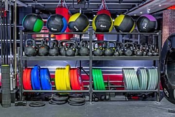 Dumbbells, pancakes and weights, leather fitballs lying on the shelves. Gym. Equipment for gym