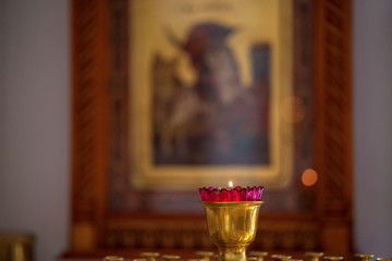 The burning candle for a prayer in Orthodox church against the background of an icon