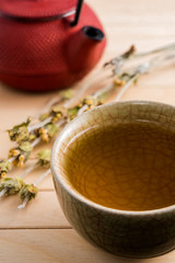 Cup of tea and japanese traditional style red teapot with dry tea on wooden table