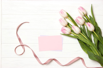 A bouquet of beautiful tulips and a card for text on a wooden background fork on top. Mother's day background, International Women's Day, birthday. Holiday, give.