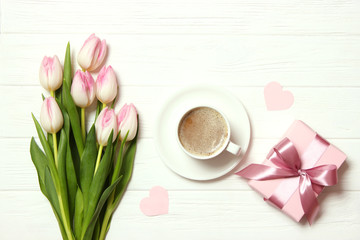 Fototapeta na wymiar bouquet of beautiful tulips, gift and coffee on wooden background top view. Mother's Day Background, International Women's Day, Birthday. Holiday, give a gift.