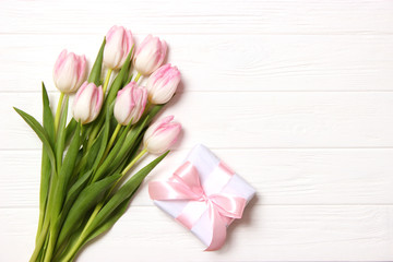 A bouquet of beautiful tulips and a gift on a wooden background top view. Mother's Day Background, International Women's Day. Holiday, give a gift.