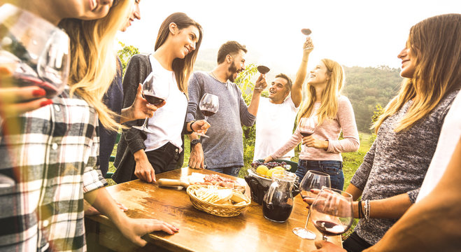 Millenial friends having fun time drinking red wine oudoors - Happy fancy people enjoying harvest at farmhouse vineyard winery - Youth friendship concept together at pic nic garden party - Warm filter