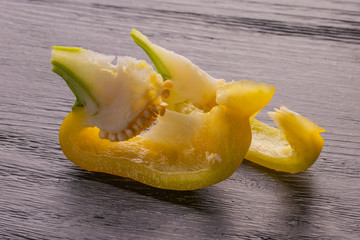 Sliced slices of yellow sweet pepper on a dark wooden table under