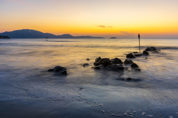 Romantic sunrise mood at silent ocean water and stones at beach