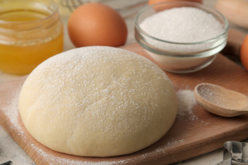 Fototapeta na wymiar baking ingredients. dough closeup and butter, eggs, sugar, milk, cinnamon, almonds on a white wooden background