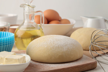 baking ingredients. dough closeup and butter, eggs, sugar, milk, cinnamon, almonds on a white wooden background