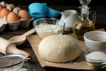 baking ingredients. baking tools. dough and butter, eggs, sugar, milk on a brown wooden background.