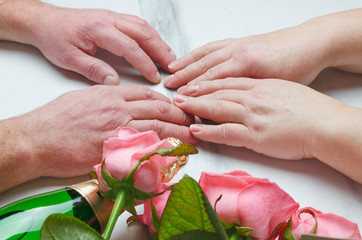 St. Valentine's Day concept.Elderly couple having a date.Bottle opf wine and flowers as a gift.Closeup shot