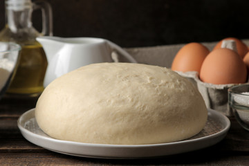 baking ingredients. baking tools. dough closeup and butter, eggs, sugar, milk on a brown wooden background.
