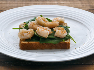 Toast with baby spinach and shrimps on plate