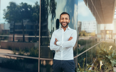 Portrait of a young confident smiling indian man with his arms crossed looking into the camera