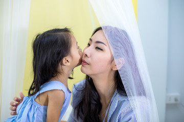 Asian girl kissing her mother in house
