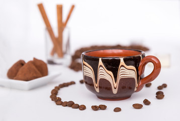 Cup of coffee with milk, coffee beans, chocolates, cinnamon sticks