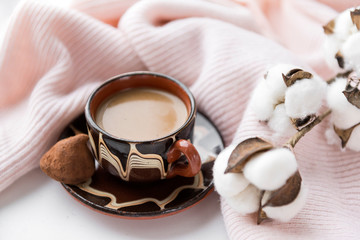 Cup of coffee with milk, candy, cotton twig, pink knitted fabric