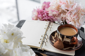 Cup, coffee with candy on the diary near the window, hydrangea flowers,