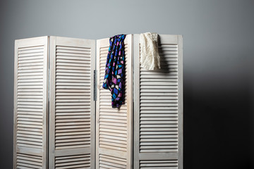 clothes hanging on the white folding screen on a gray background