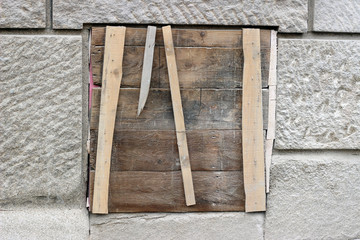 Window boarded shut wood plank grey gray brown building stone wall