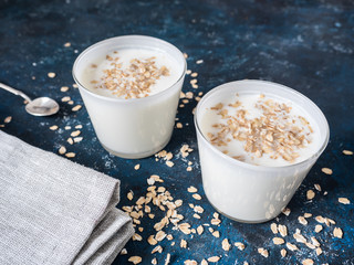 Healthy breakfast. Yogurt with oat flakes in white glasses on a blue background.