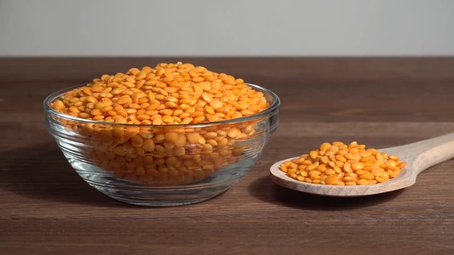 Lentejas naranjas crudas en un bol en la mesa de madera