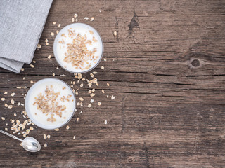 Fototapeta na wymiar Healthy breakfast. Yogurt with oat flakes in white glasses on a wooden table