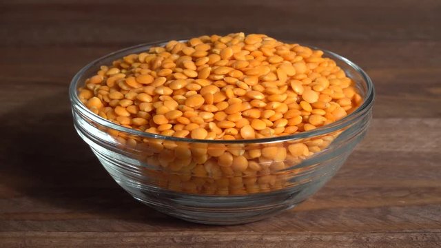 Lentejas naranjas crudas en un bol en la mesa de madera