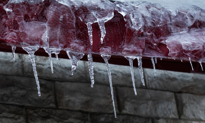 Small icicles spike of ice hanging from the roof element. Subfreezing weather concept.
