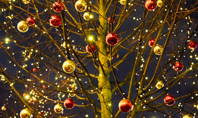 Beautiful Xmas tree decorated with glowing garland, red and gold balls. Soft focus
