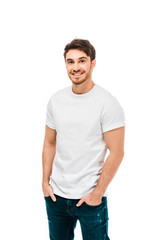 handsome happy young man standing with hands in pockets and smiling at camera isolated on white