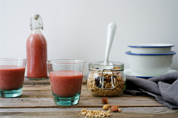 Breakfast with granola and strawberry banana smoothie. Rustic wooden table, white background